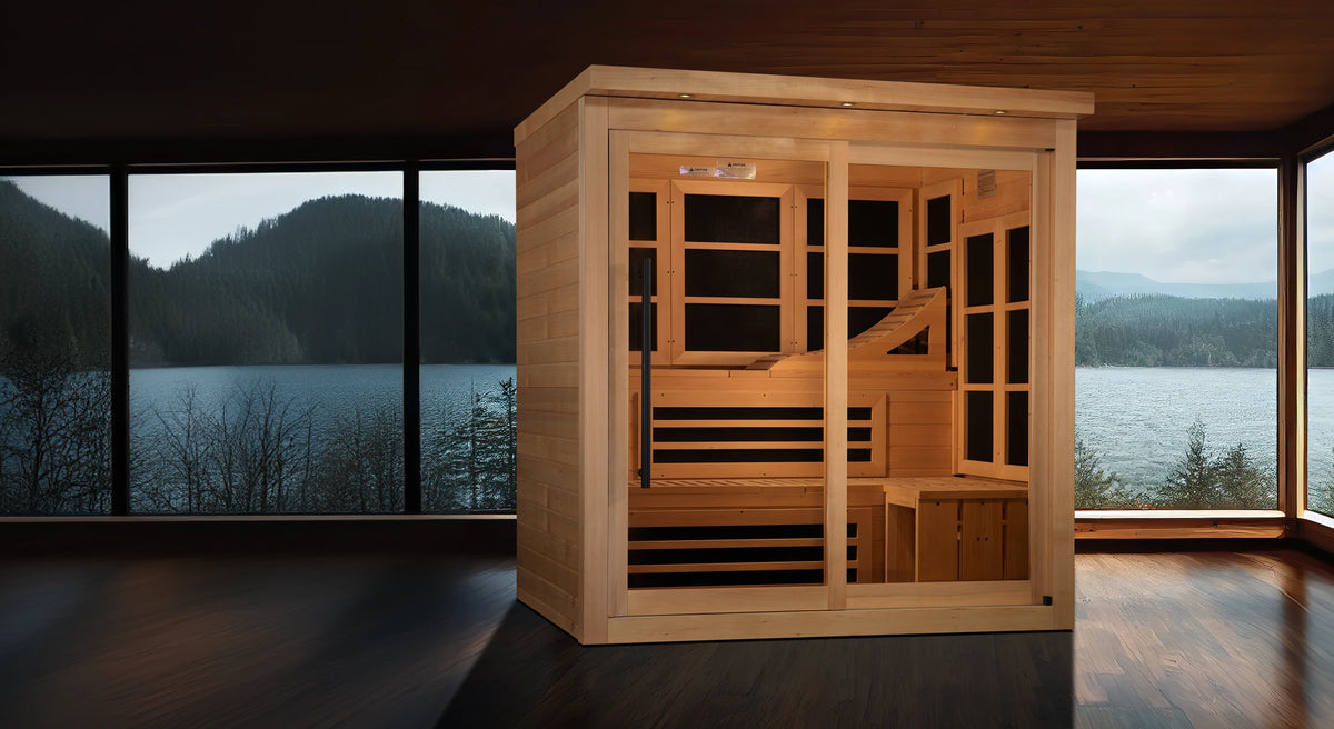 Golden Designs Monaco model FAR infrared sauna with a six person capacity constructed from Canadian hemlock wood in a dimly lit room with large windows overlooking a lake